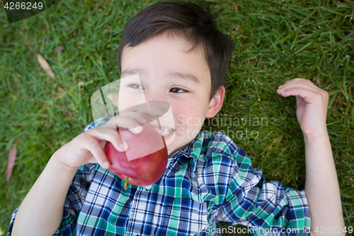 Image of Mixed Race Chinese and Caucasian Young Boy With Apple Relaxing O