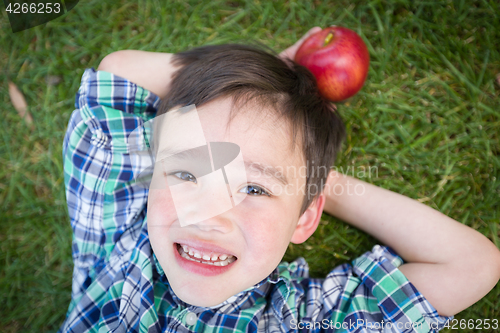 Image of Mixed Race Chinese and Caucasian Young Boy With Apple Relaxing O