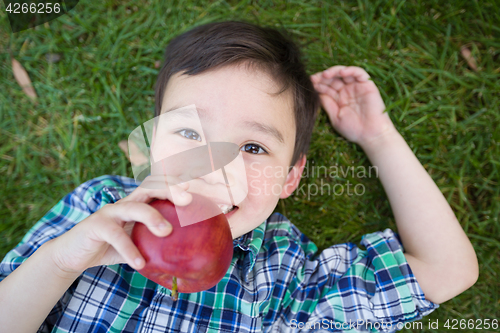 Image of Mixed Race Chinese and Caucasian Young Boy With Apple Relaxing O