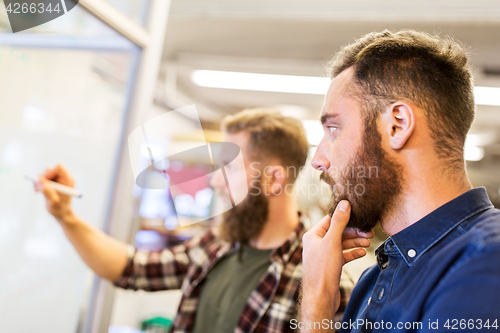 Image of men writing to whiteboard at office