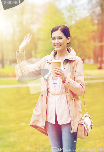 Image of smiling woman drinking coffee in park