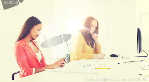 Image of businesswoman texting on smartphone at office