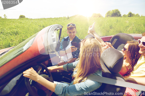 Image of friends driving in car and photographing