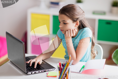 Image of bored girl with laptop and notebook at home