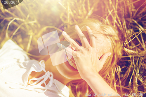 Image of happy young woman lying on cereal field