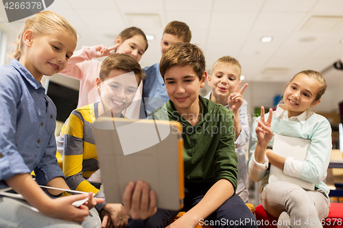 Image of group of happy children with tablet pc at school