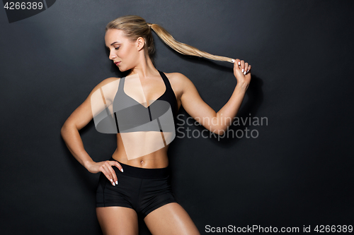 Image of young woman in black sportswear posing in gym
