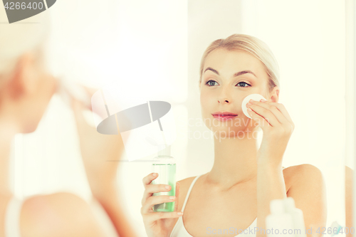 Image of young woman with lotion washing face at bathroom