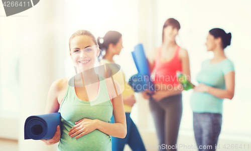 Image of happy pregnant woman with mat in gym