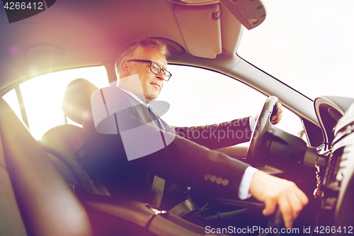 Image of happy senior businessman driving car