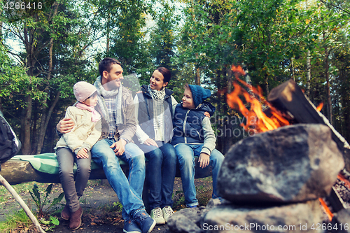 Image of happy family sitting on bench at camp fire