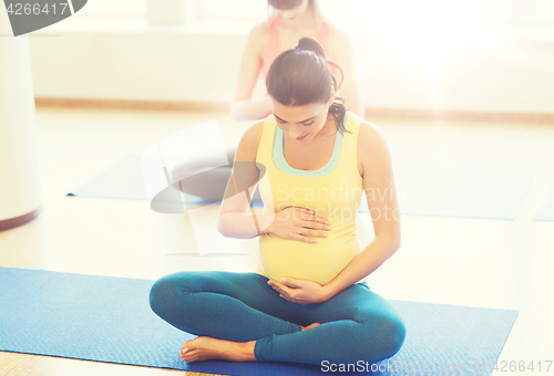 Image of happy pregnant women exercising yoga in gym