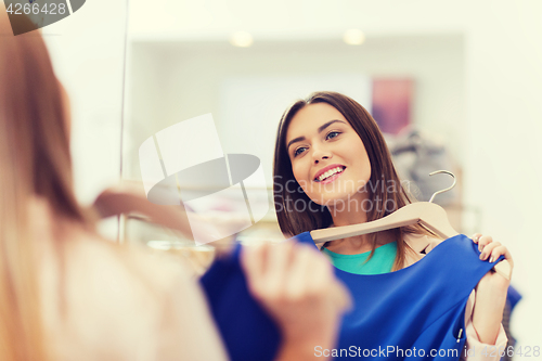 Image of happy woman with clothes at clothing store mirror