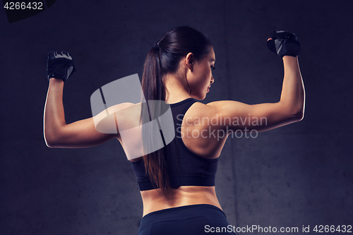 Image of young woman flexing muscles in gym