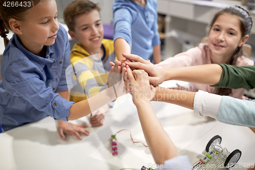 Image of happy children making high five at robotics school