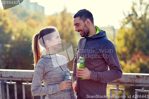 Image of smiling couple with bottles of water outdoors