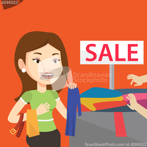 Image of Young woman choosing clothes in shop on sale.