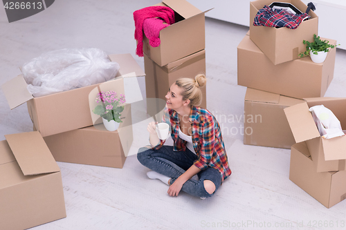 Image of woman with many cardboard boxes sitting on floor