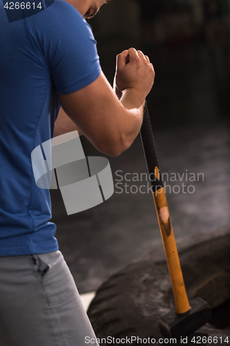 Image of man workout with hammer and tractor tire