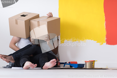 Image of young multiethnic couple playing with cardboard boxes