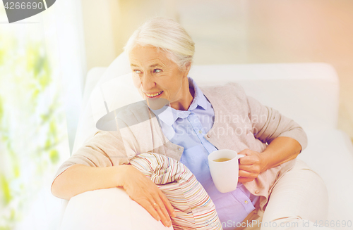 Image of happy senior woman with cup of tea at home