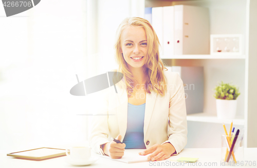 Image of businesswoman writing to notebook at office