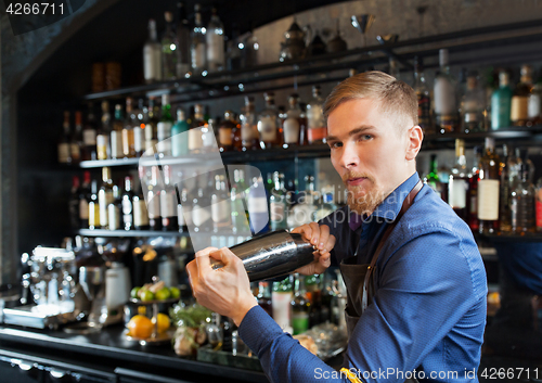 Image of barman with shaker preparing cocktail at bar