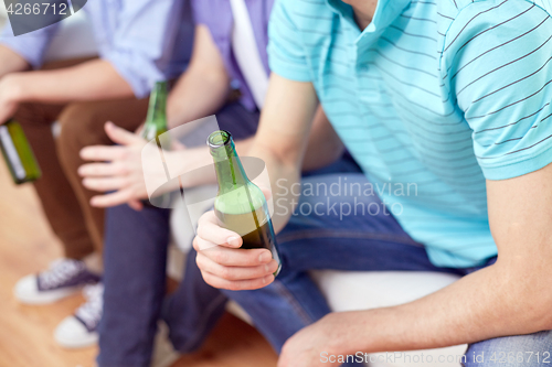 Image of men with beer bottles sitting on sofa at home