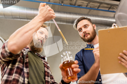 Image of men with pipette testing craft beer at brewery