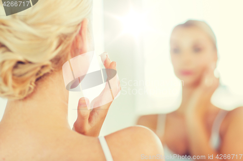 Image of close up of woman applying face cream at bathroom