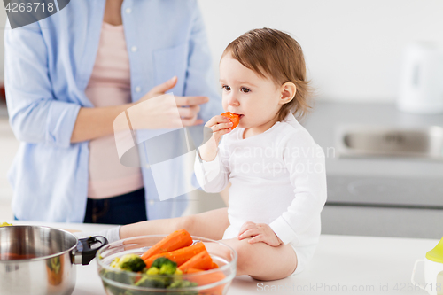 Image of happy mother and baby eating at home kitchen