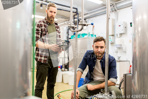 Image of men with tablet pc at craft beer brewery kettle