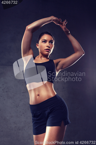 Image of young woman posing and showing muscles in gym