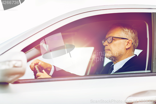 Image of happy senior businessman driving car