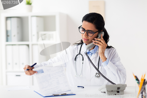 Image of doctor with clipboard calling on phone at hospital