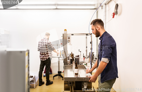 Image of men with bottles on conveyor at craft beer brewery