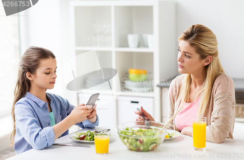 Image of sad woman looking at her daughter with smartphone