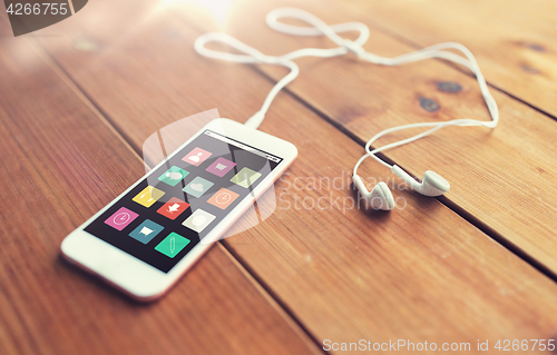 Image of close up of smartphone and earphones on wood