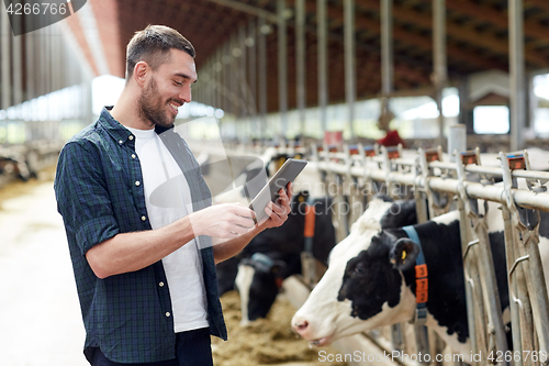 Image of young man with tablet pc and cows on dairy farm