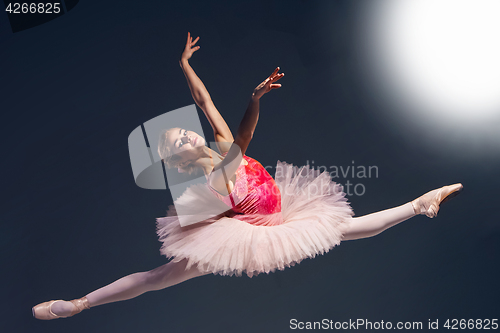 Image of Beautiful female ballet dancer on a dark background. Ballerina is wearing pink tutu and pointe shoes.