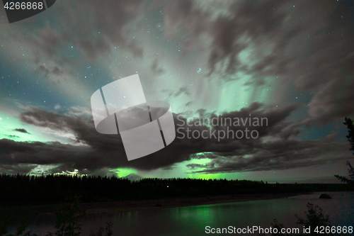 Image of The Aurora Borealis emerges through clouds remote Alaska