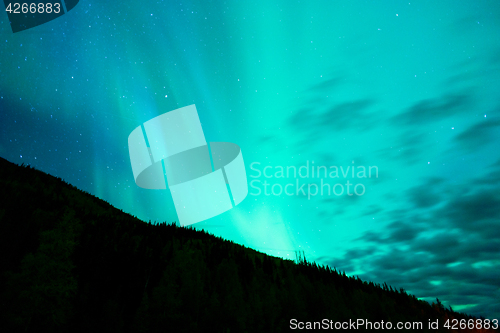 Image of The Aurora Borealis emerges through clouds remote Alaska