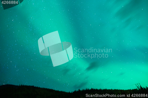 Image of The Aurora Borealis emerges through clouds remote Alaska