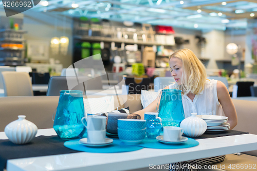 Image of Woman choosing the right decor for her apartment in a modern home furnishings store.