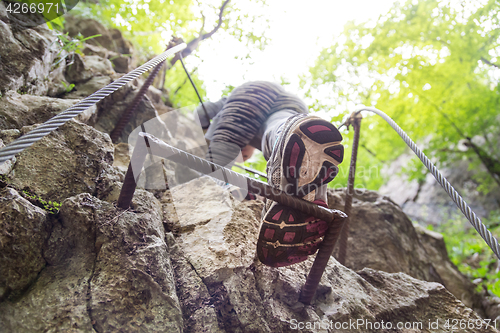 Image of Woman climbing on the rocky route up the mountain.