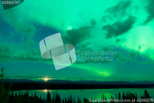 Image of The Aurora Borealis emerges through clouds remote Alaska