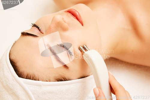 Image of Cosmetology. Beautiful Woman At Spa Clinic Receiving Stimulating Electric Facial Treatment From Therapist. Closeup Of Young Female Face During Microcurrent Therapy. Beauty Treatment.