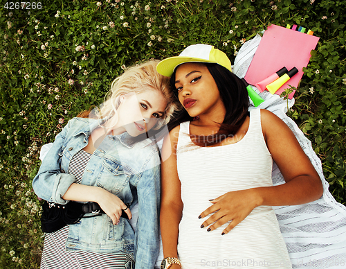 Image of two young pretty teenager girls best friends laying on grass mak