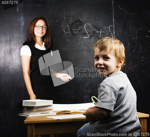 Image of little cute boy with teacher in classroom