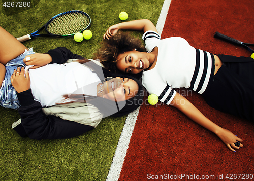 Image of young pretty girlfriends hanging on tennis court, fashion stylis